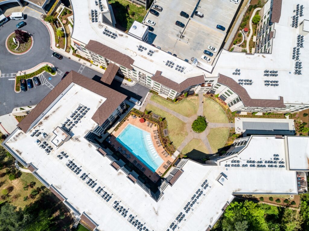 Sky view of apartment community with view of courtyard, pool, and parking
