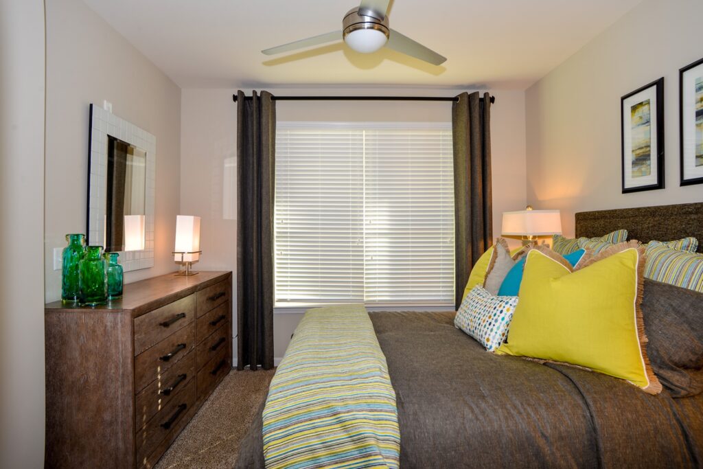 Bedroom with large window, ceiling fan, and carpet floors.