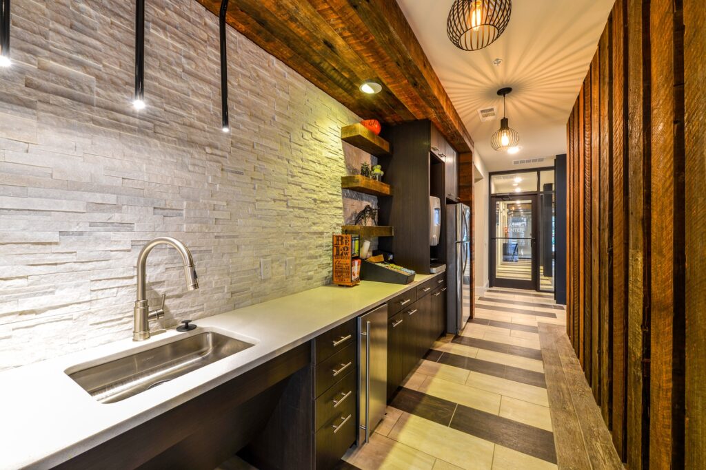 Club house kitchen area with coffee maker, fridge, and sink. Wooden accent wall