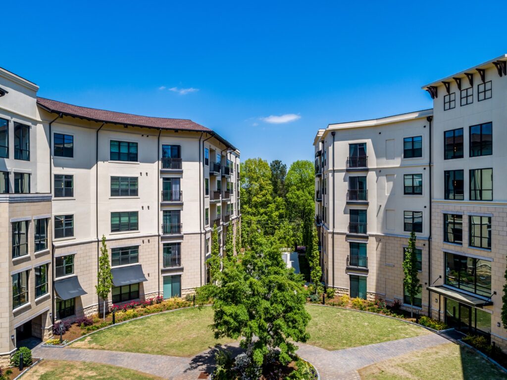 View of middle of courtyard with residential building on each side. with bocce ball court in the middle of the 2 buildings.