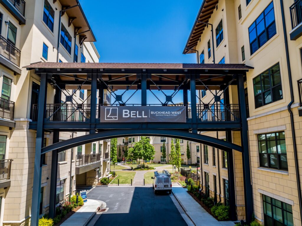Bell buckhead west sky bridge connecting residential buildings with driveway going underneath.