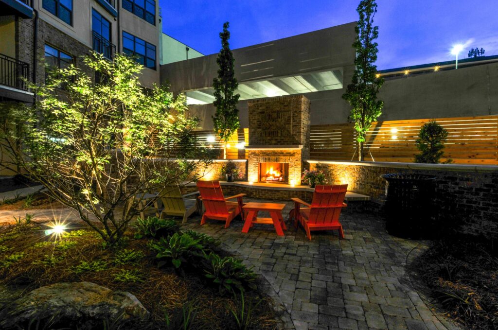 Night view of outdoor fire place with chairs and side tables.