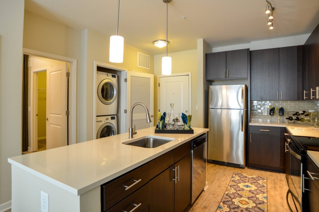 Kitchen island with granite counter tops, stainless steel appliances, and with stacked washer and dryer.