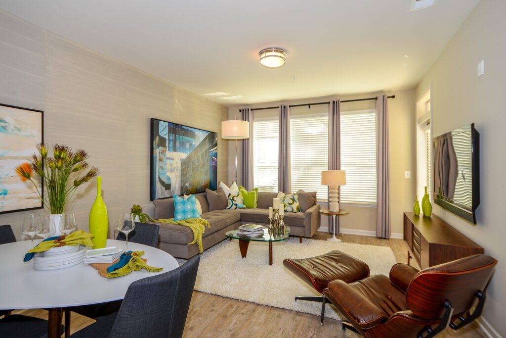 Living room with large windows, wood floors, and view of dining area.