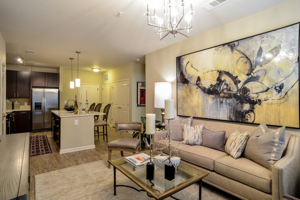 Living room with hanging light fixture and view of kitchen island with granite counter tops with bar seating, and stainless steel appliances.