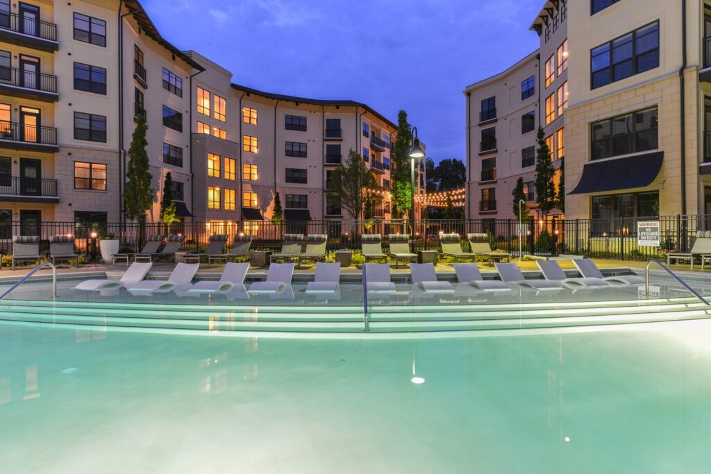 In pool lounge chairs with view of pool. Lounge chairs on the outside of pool and residential building in back