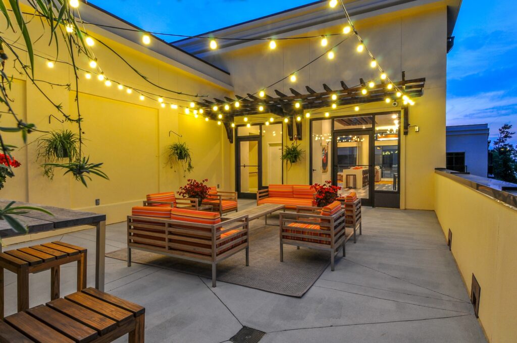 Out door seating area at night with string lights and table with stools.